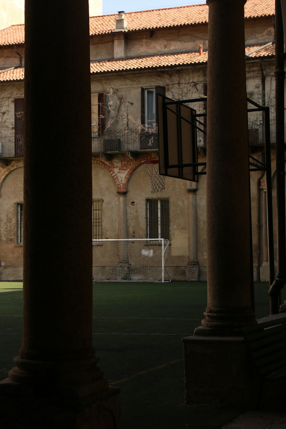 a view of a basketball court through some pillars