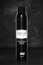 A sleek black bottle of perfumed deodorant body spray for women, labeled 'Good Girl' by Carolina Herrera, with the text 'It's so good to be bad' above the brand name. The bottle stands upright against a dark, textured background.
