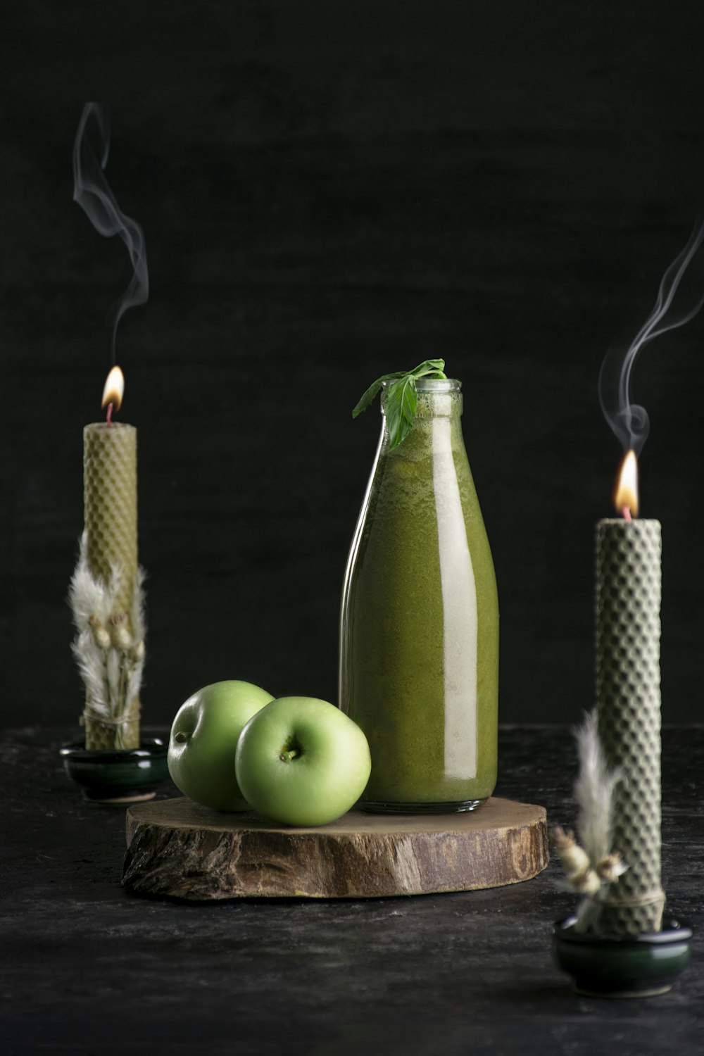 a bottle of green liquid next to two candles
