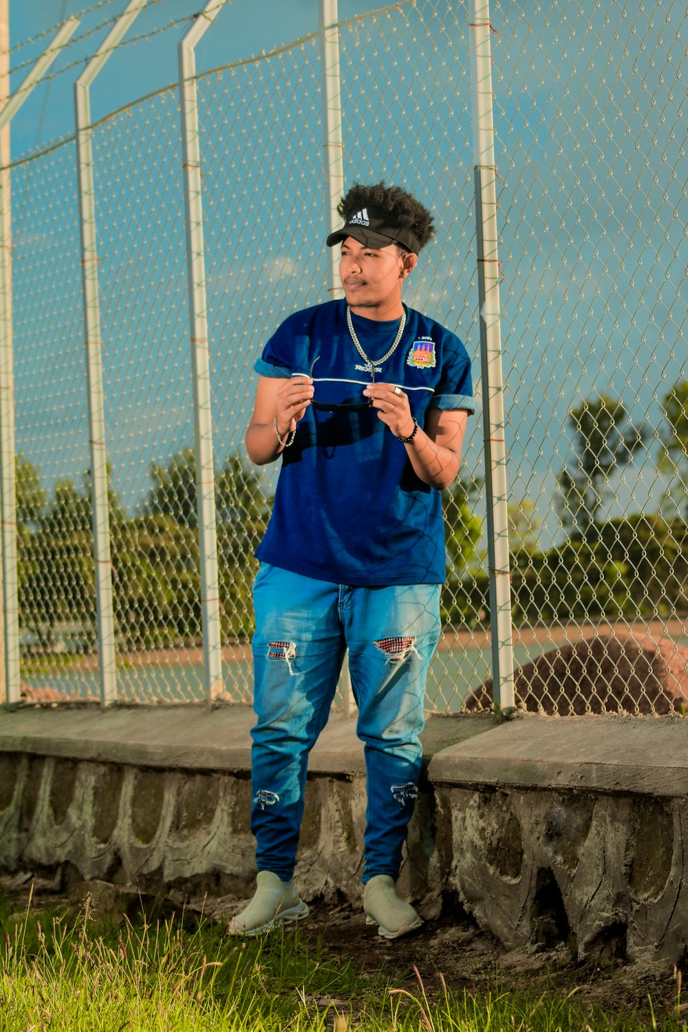 a man standing in front of a chain link fence