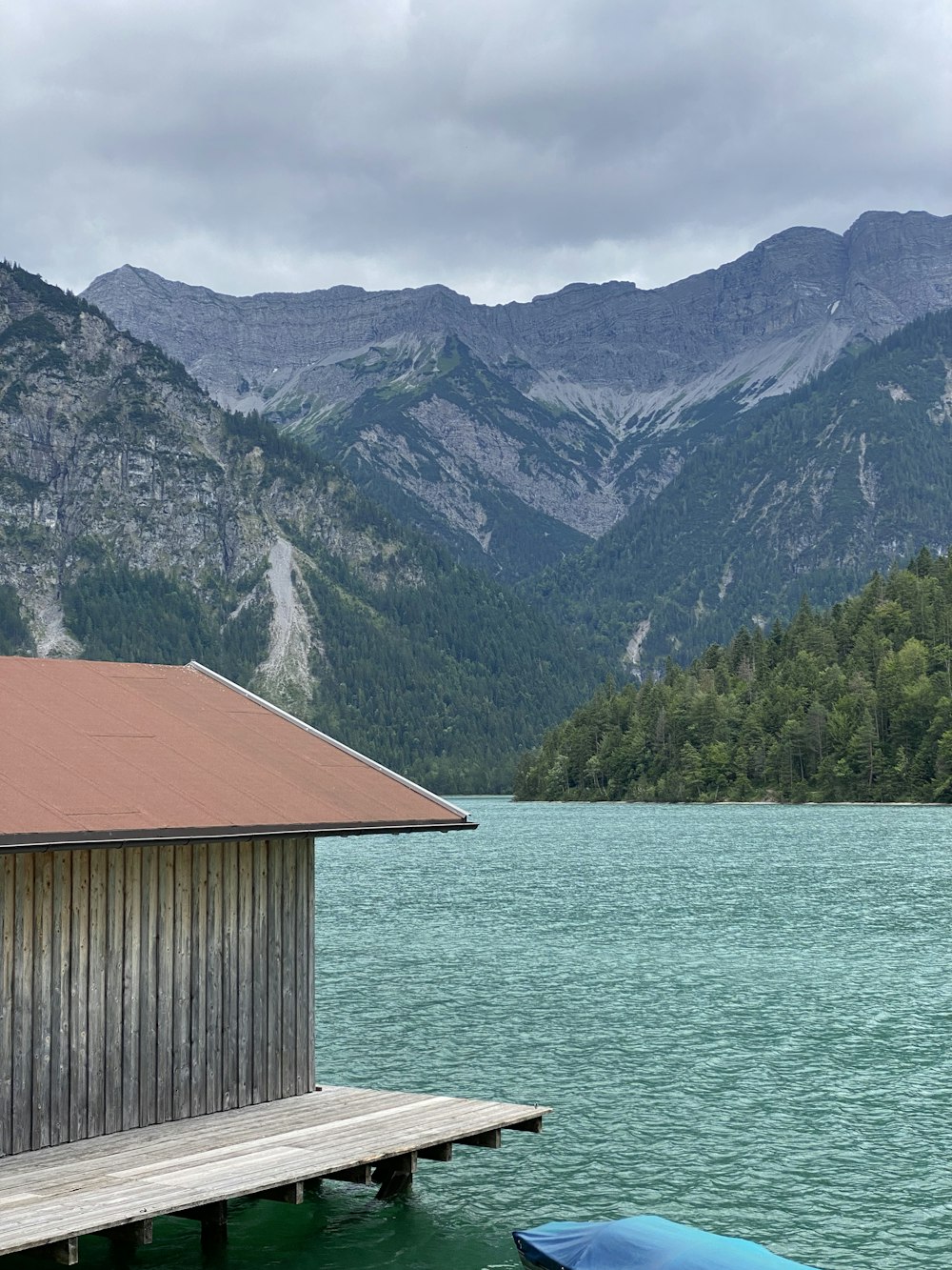 a wooden dock sitting next to a lake with mountains in the background