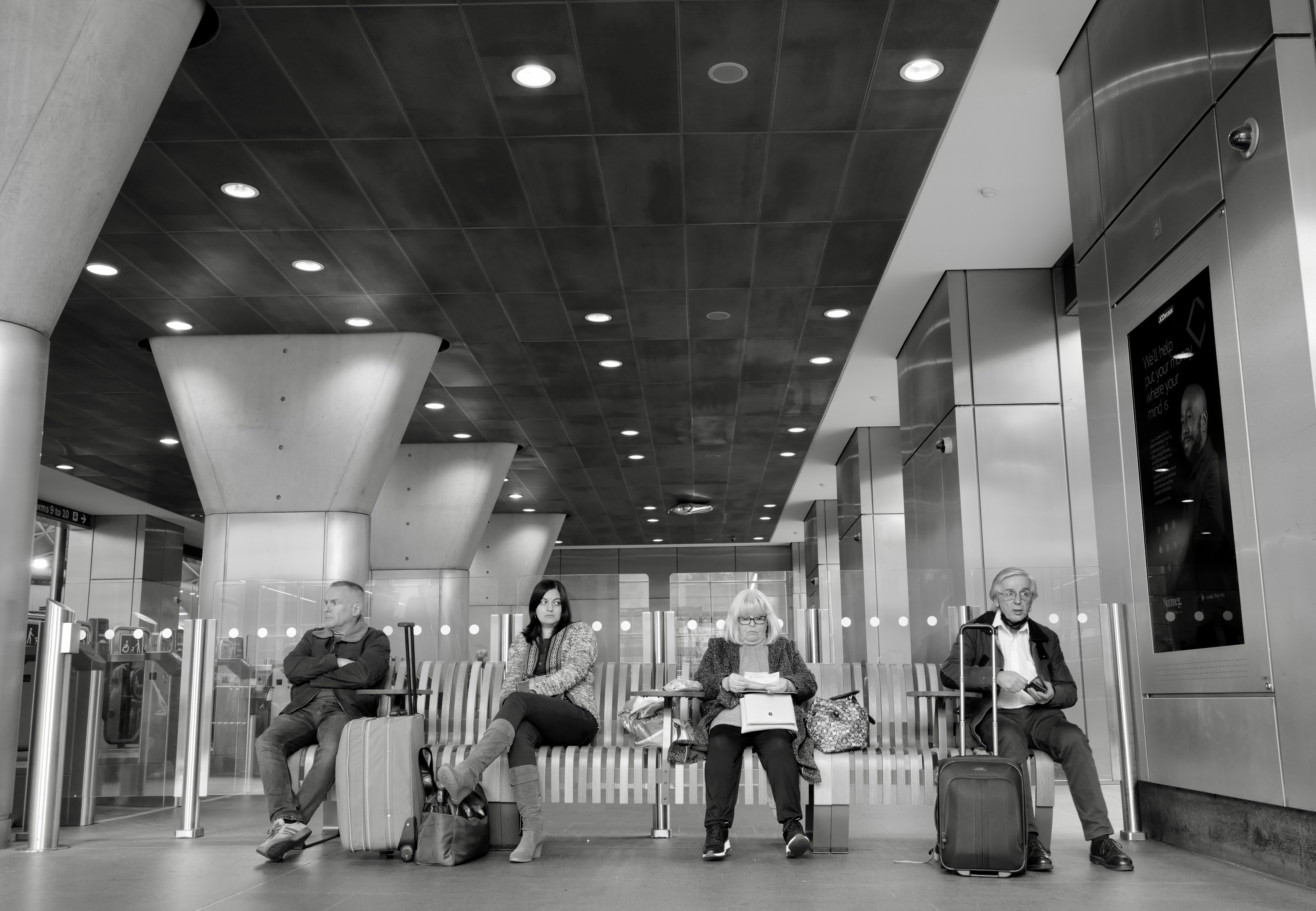a black and white photo of people waiting for their luggage