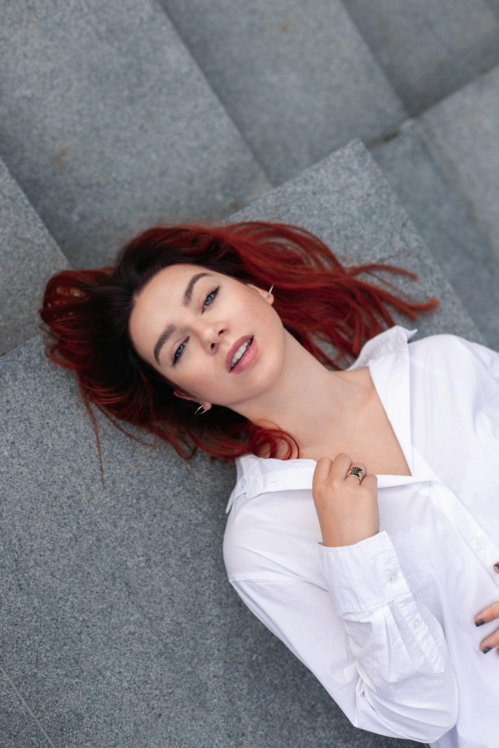 a woman with red hair is laying on the ground