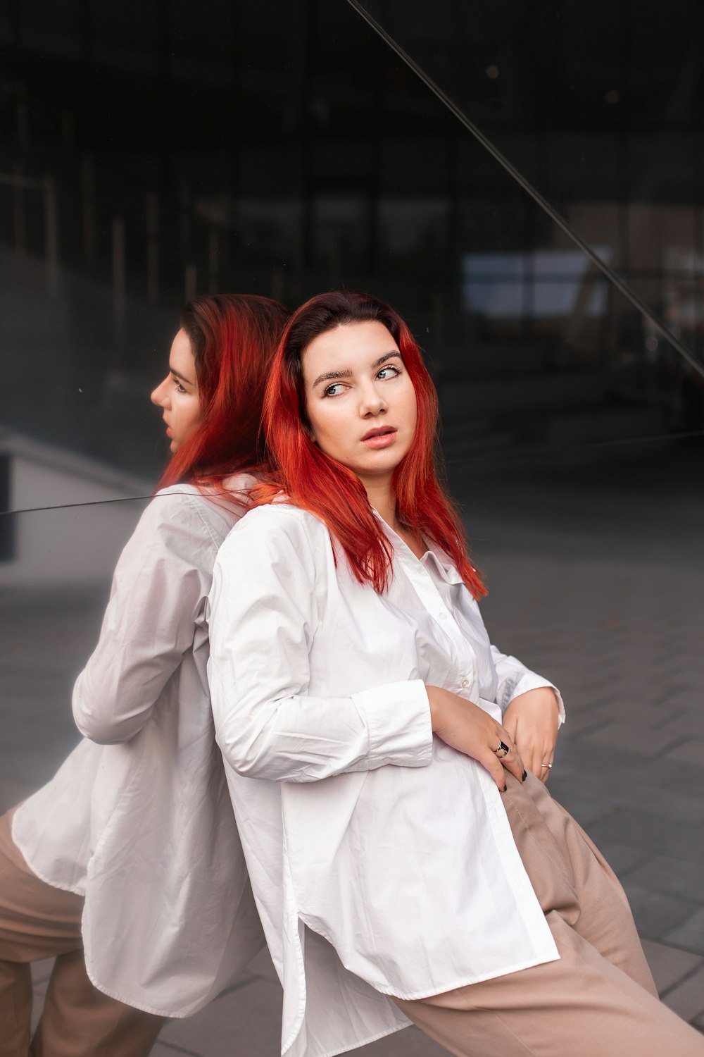 Une femme aux cheveux roux assise sur un banc