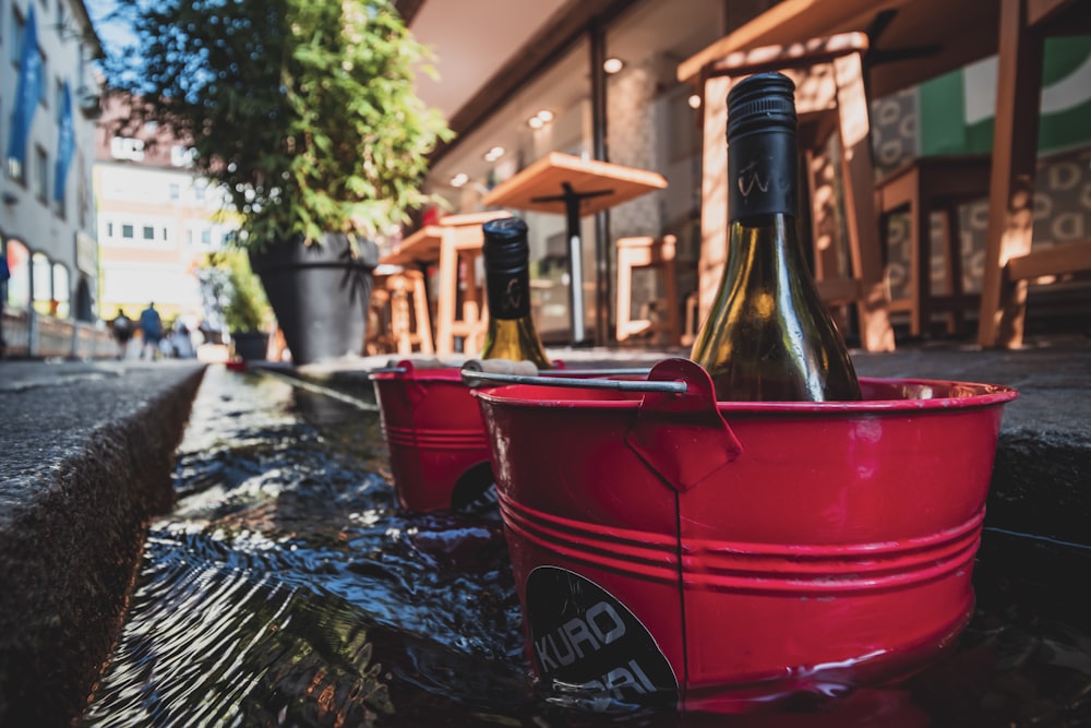 a red bucket with two bottles of wine in it