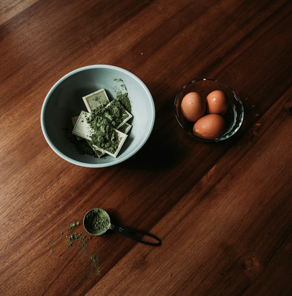 a wooden table with a bowl of food and eggs