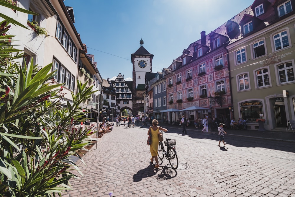 a woman riding a bike down a cobblestone street