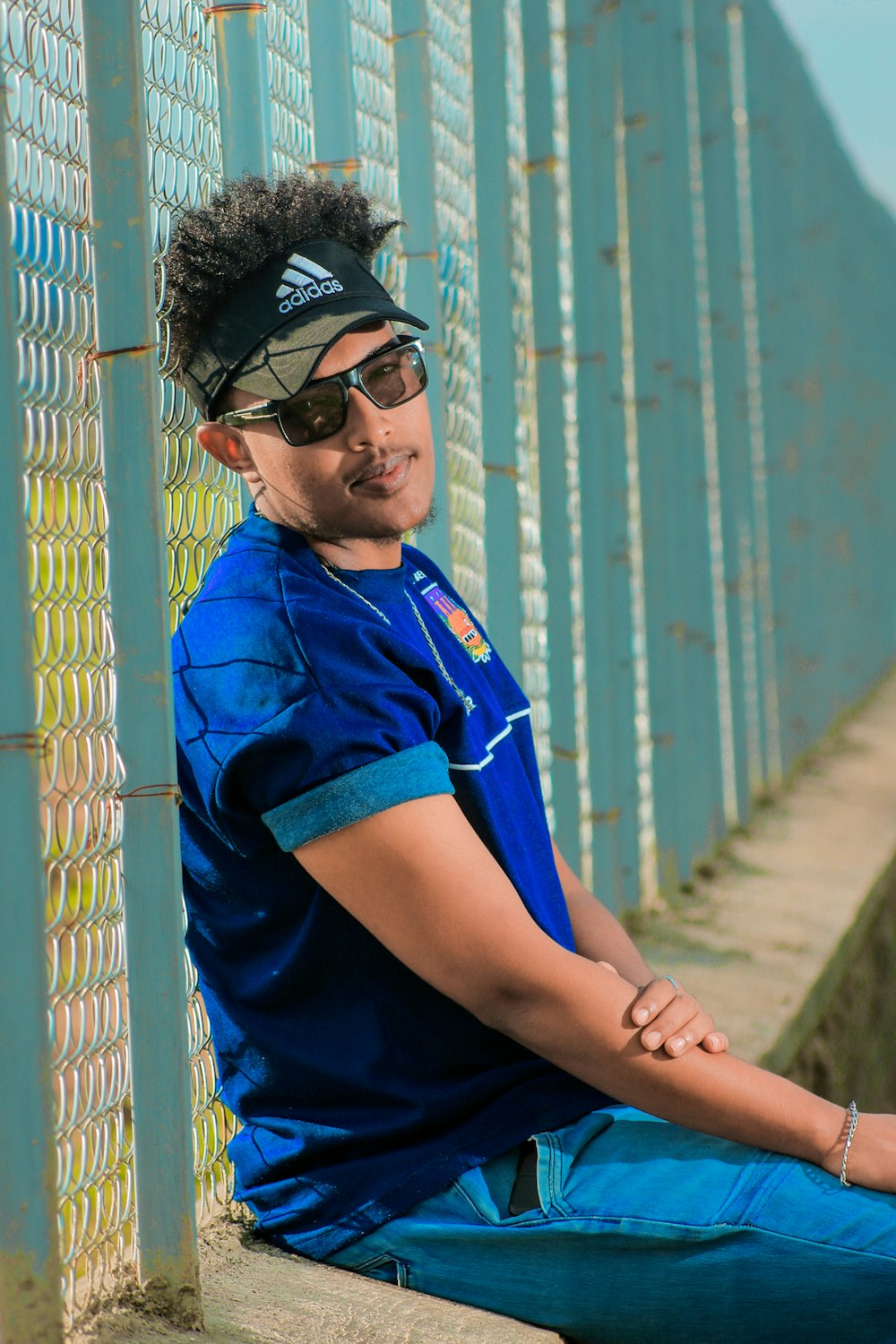 a man in a blue shirt sitting on a wall