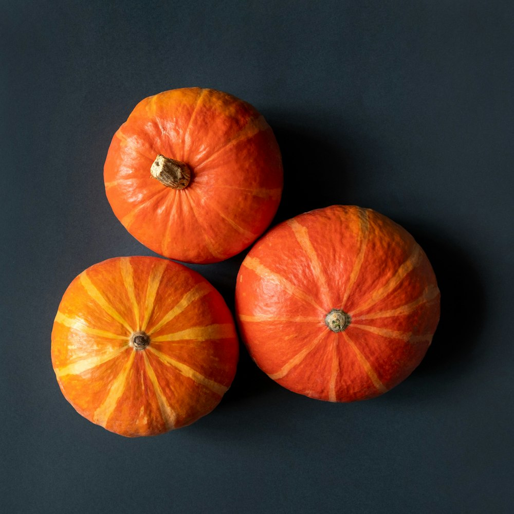 three oranges sitting on top of a black surface