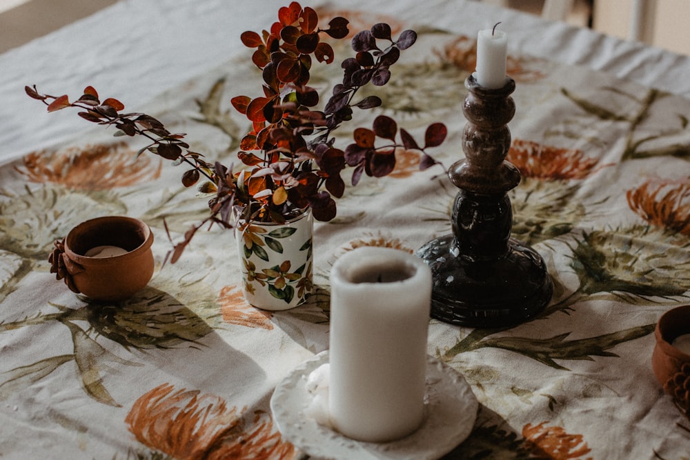 a table topped with two candles and a vase filled with flowers
