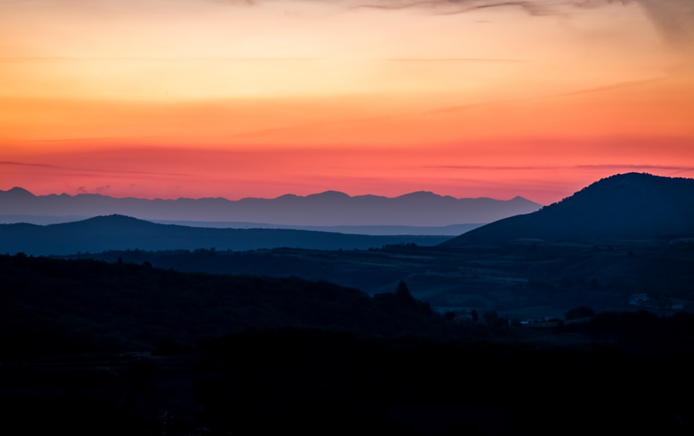 the sun is setting over a mountain range