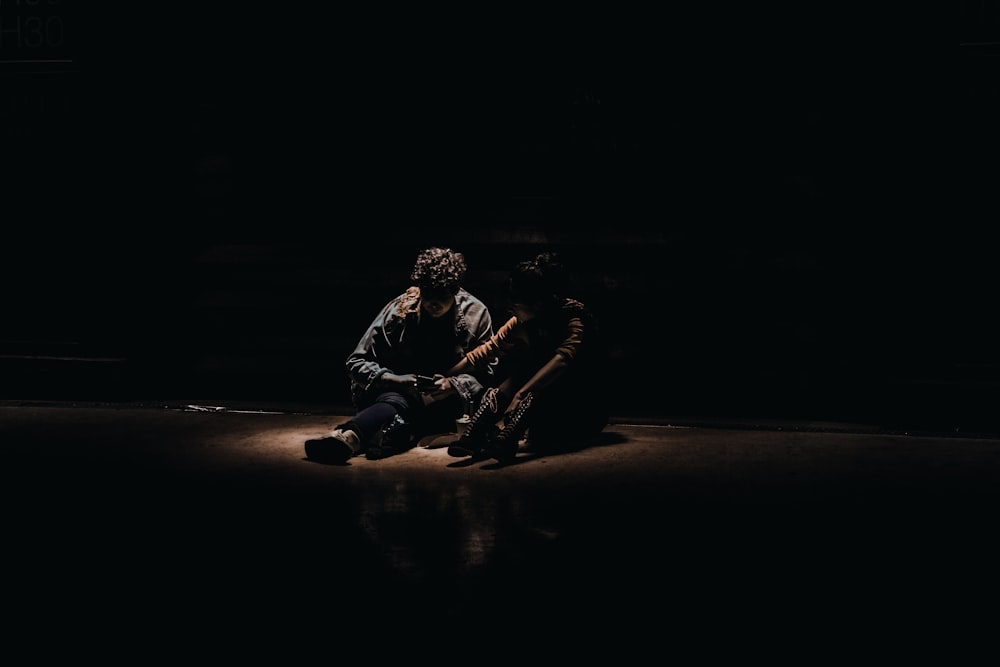 two people sitting on the floor in the dark