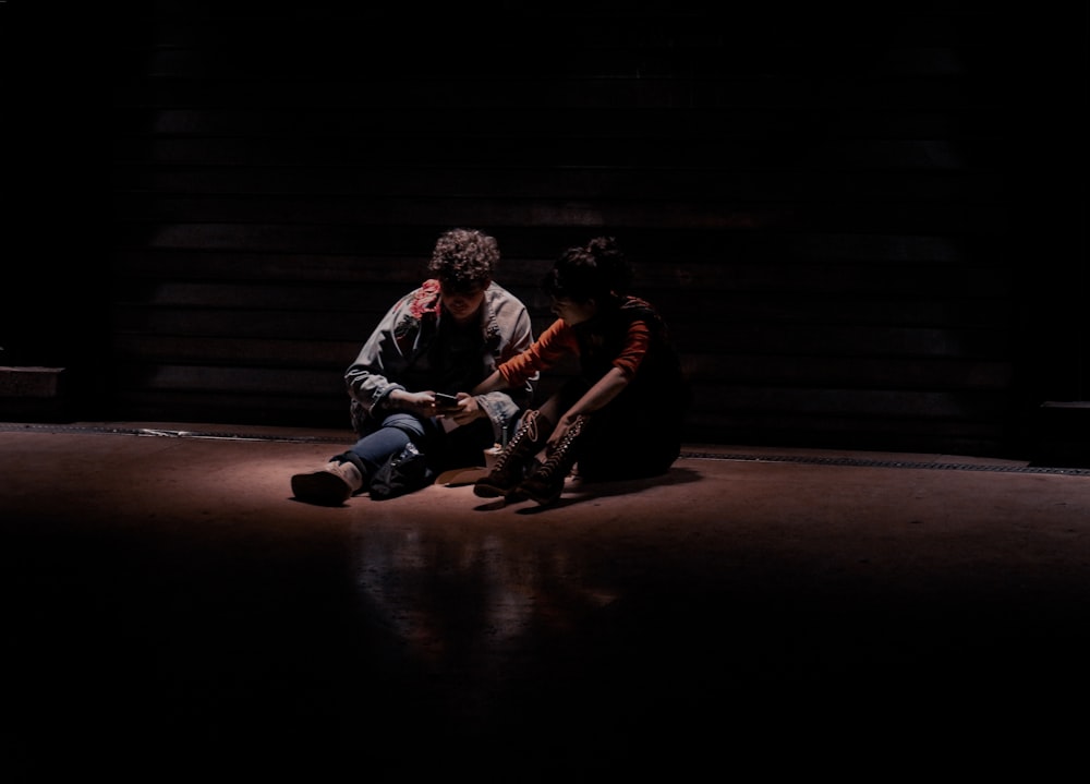 two people sitting on the floor in the dark