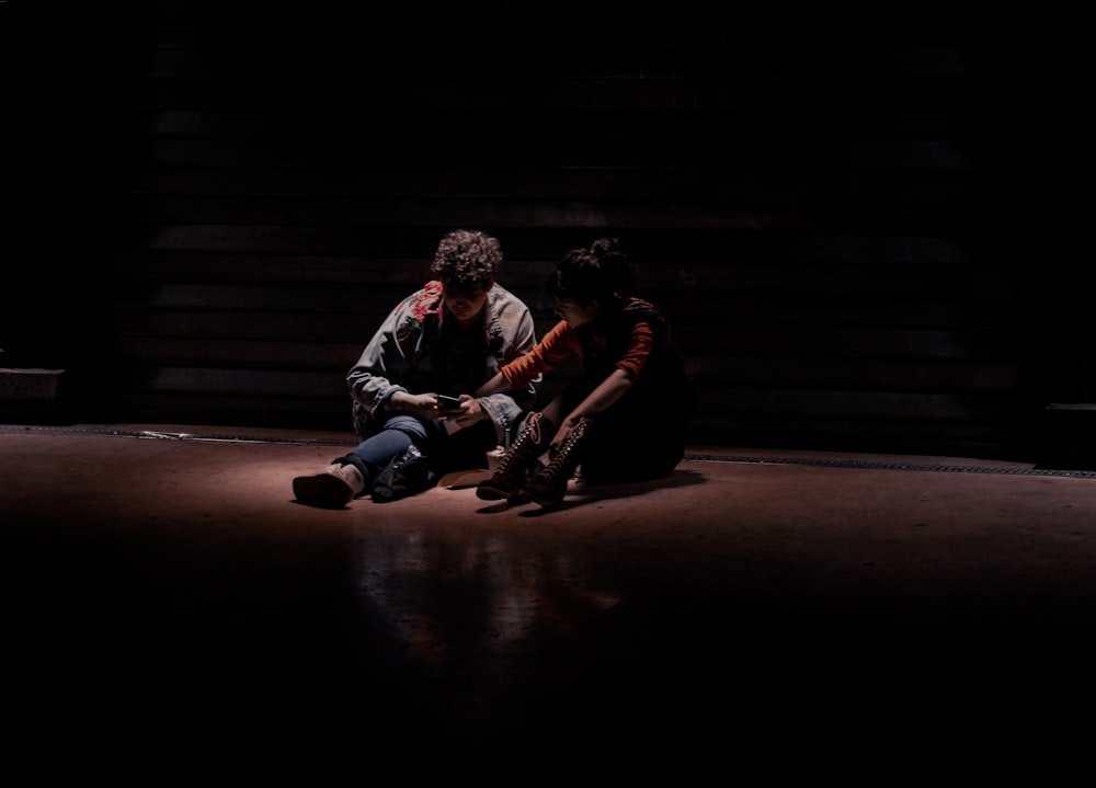 Dos personas sentadas en el suelo en la oscuridad