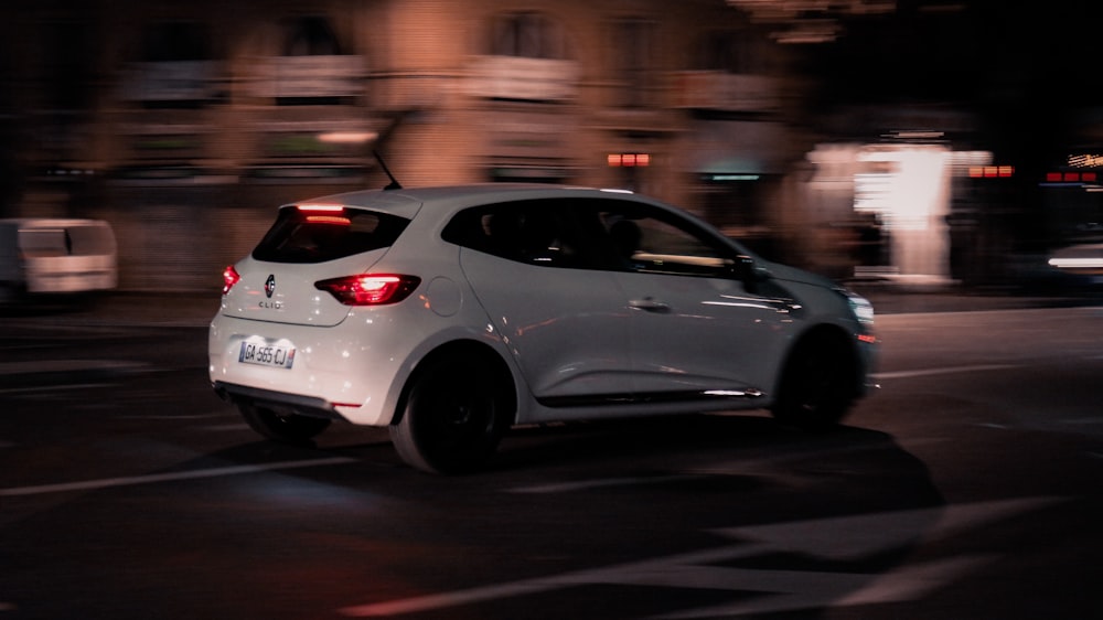 a white car driving down a street at night