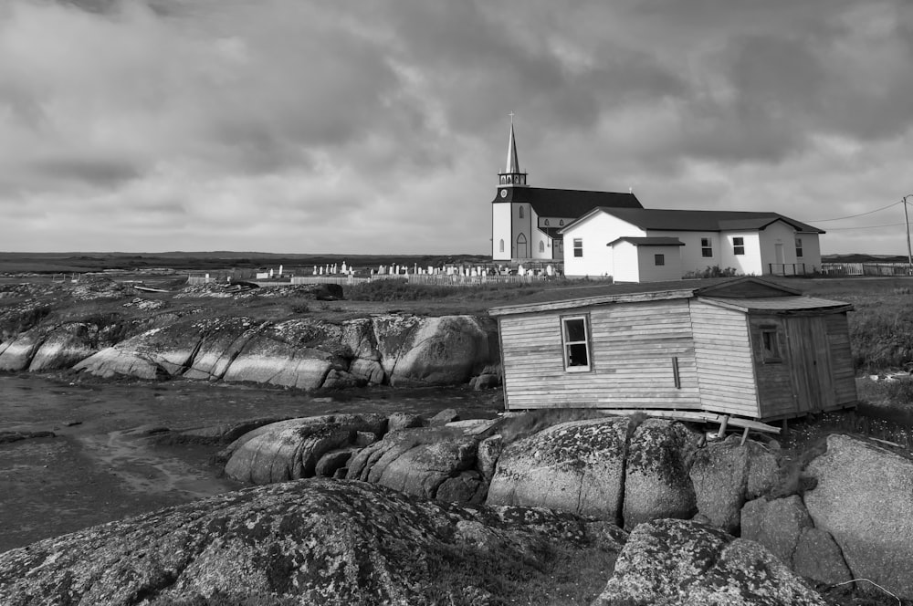 a black and white photo of a church on a rocky shore