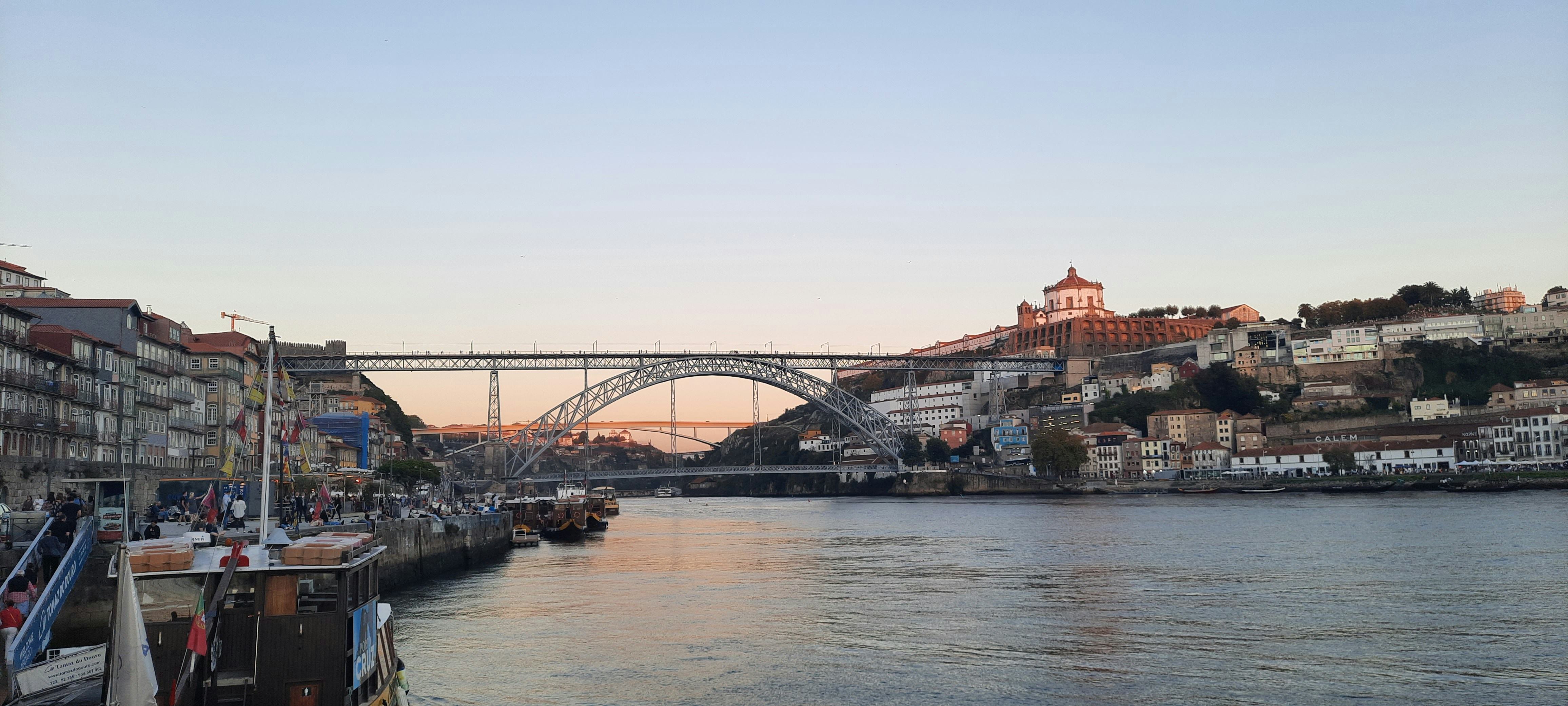Ribeira de Oporto con casas coloridas reflejadas en río Duero, puente Luis I al fondo, barcos rabelo