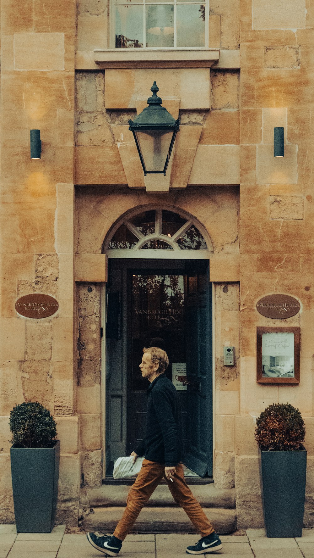 a man walking down a sidewalk past a tall building