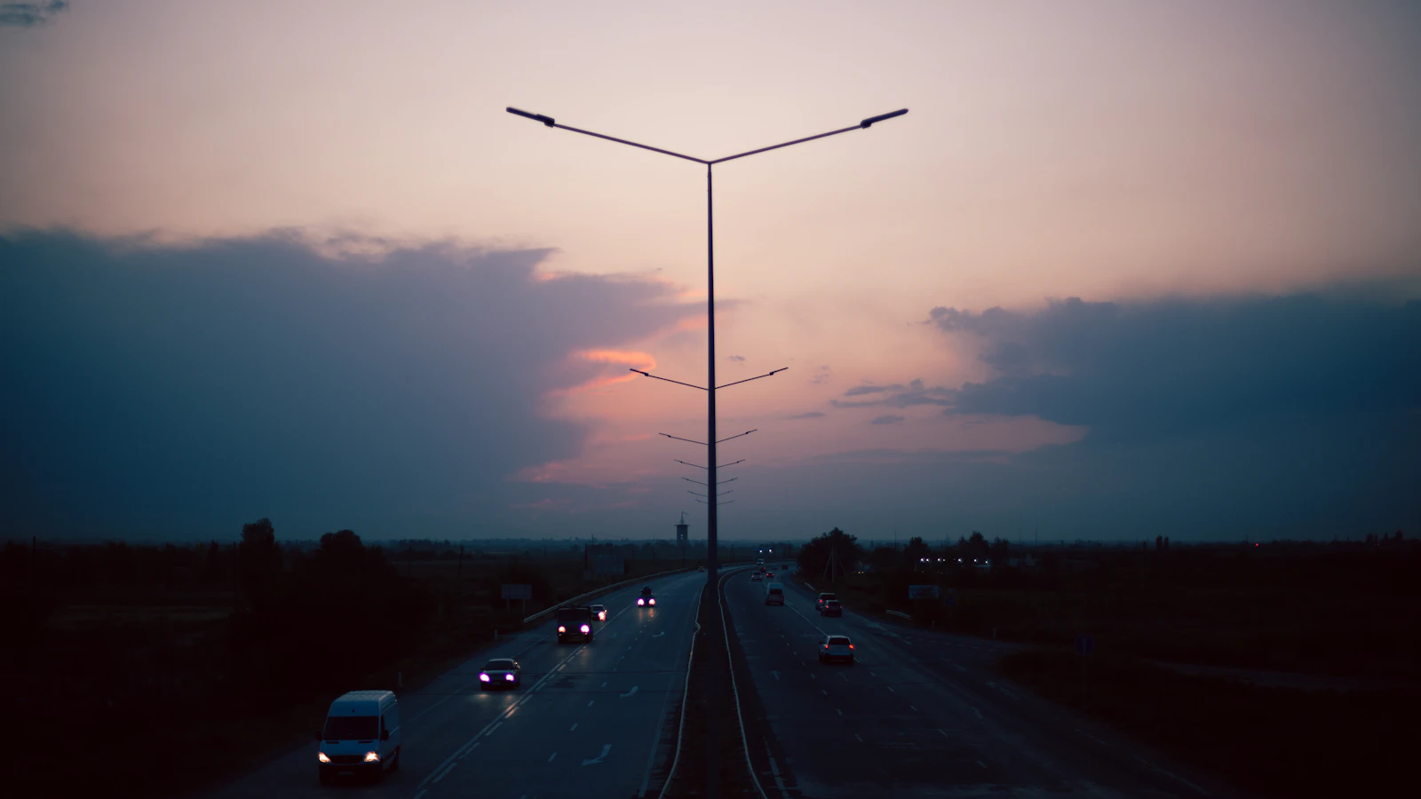 The sun is setting over a highway with traffic