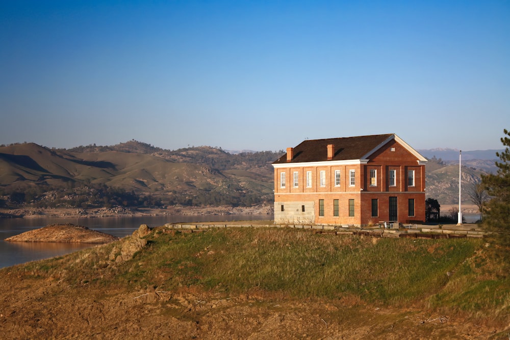 a house sitting on top of a hill next to a lake