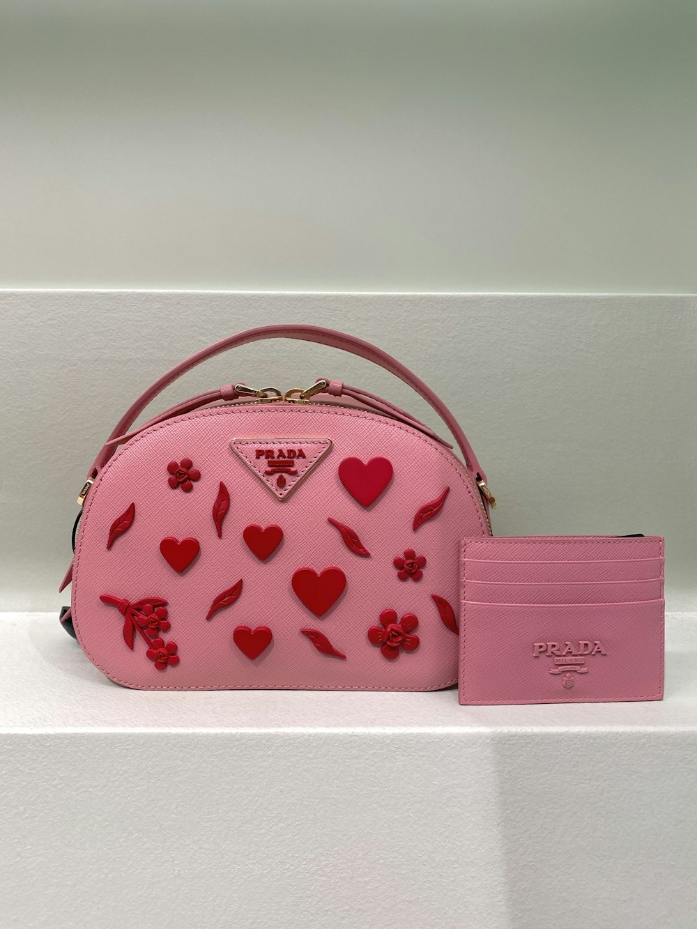 un sac à main rose avec des cœurs et des fleurs dessus