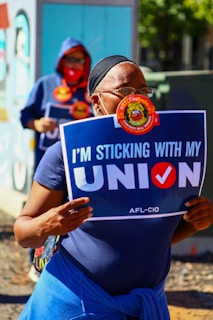a woman holding a sign that says i'm sticking with my union