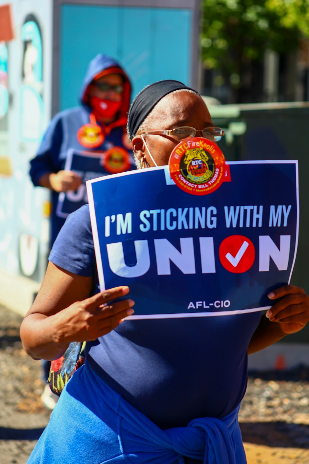 a woman holding a sign that says i'm sticking with my union