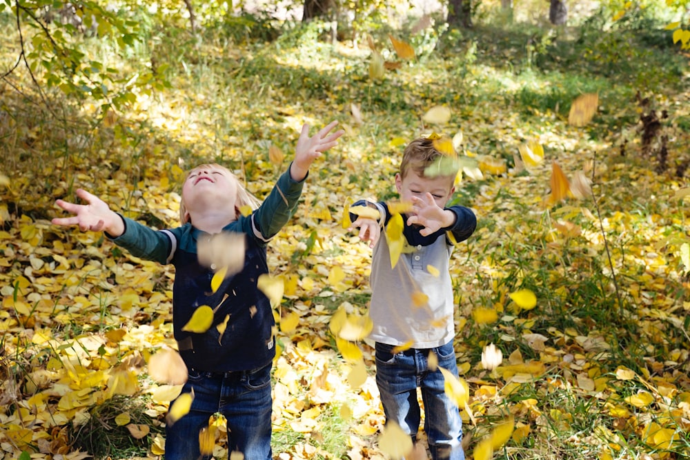 Dos niños pequeños jugando con hojas en el bosque