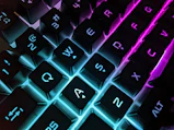 Close-up of a mechanical keyboard with neon blue backlight on black background