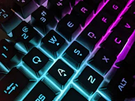 Close-up of a mechanical keyboard with glowing neon blue backlight and crisp keycaps