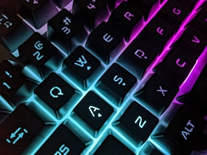 A close-up of a mechanical keyboard with colorful backlighting glowing in a dim room.