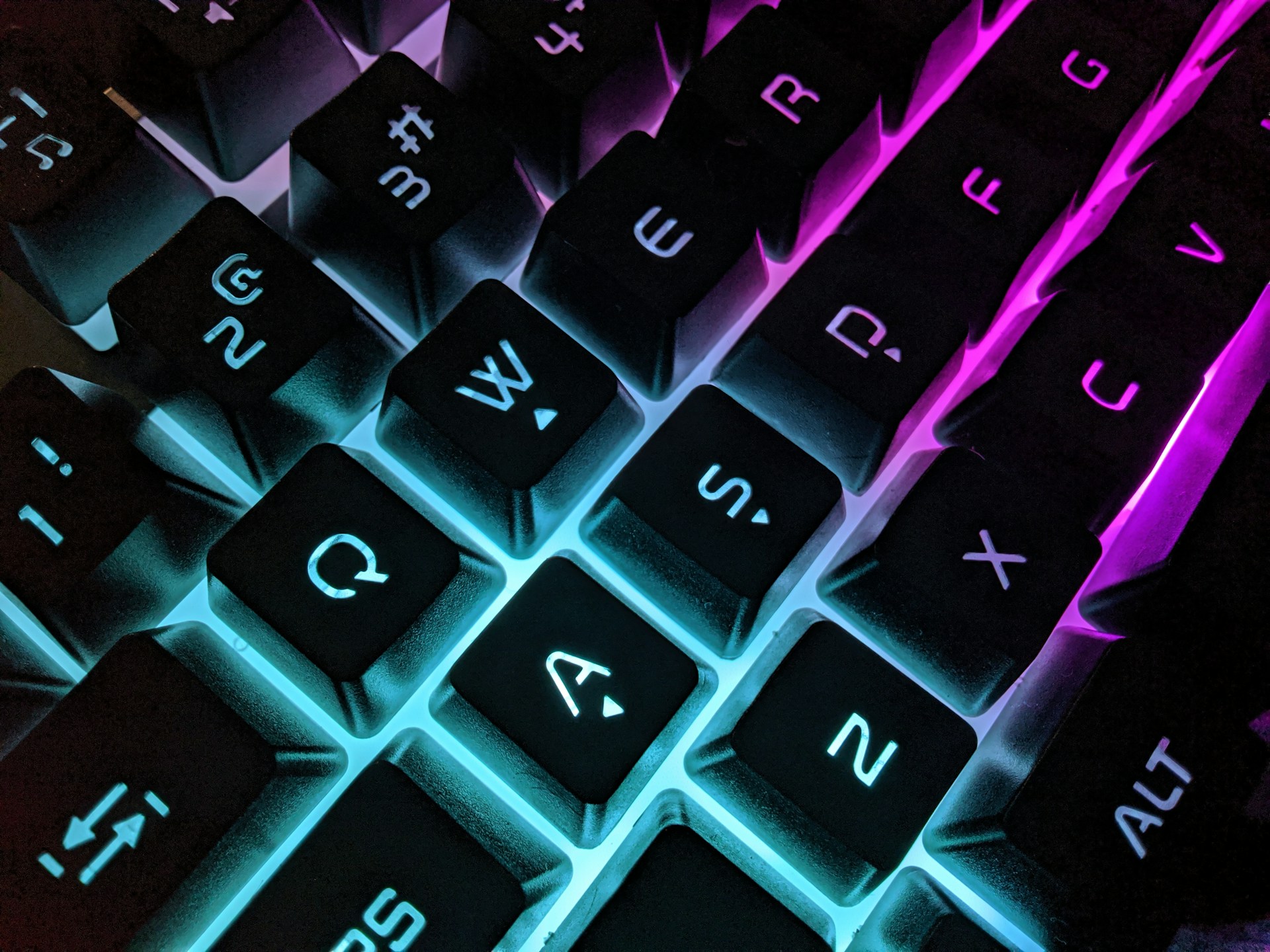 Close-up of a mechanical RGB keyboard with dynamic lighting effects illuminating each key in neon blue and purple hues.