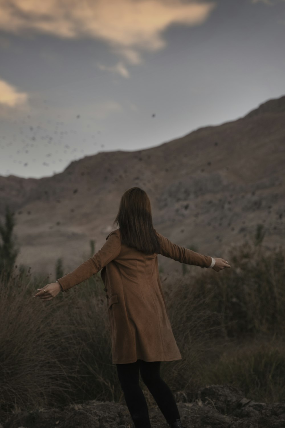 a woman standing in a field with her arms outstretched