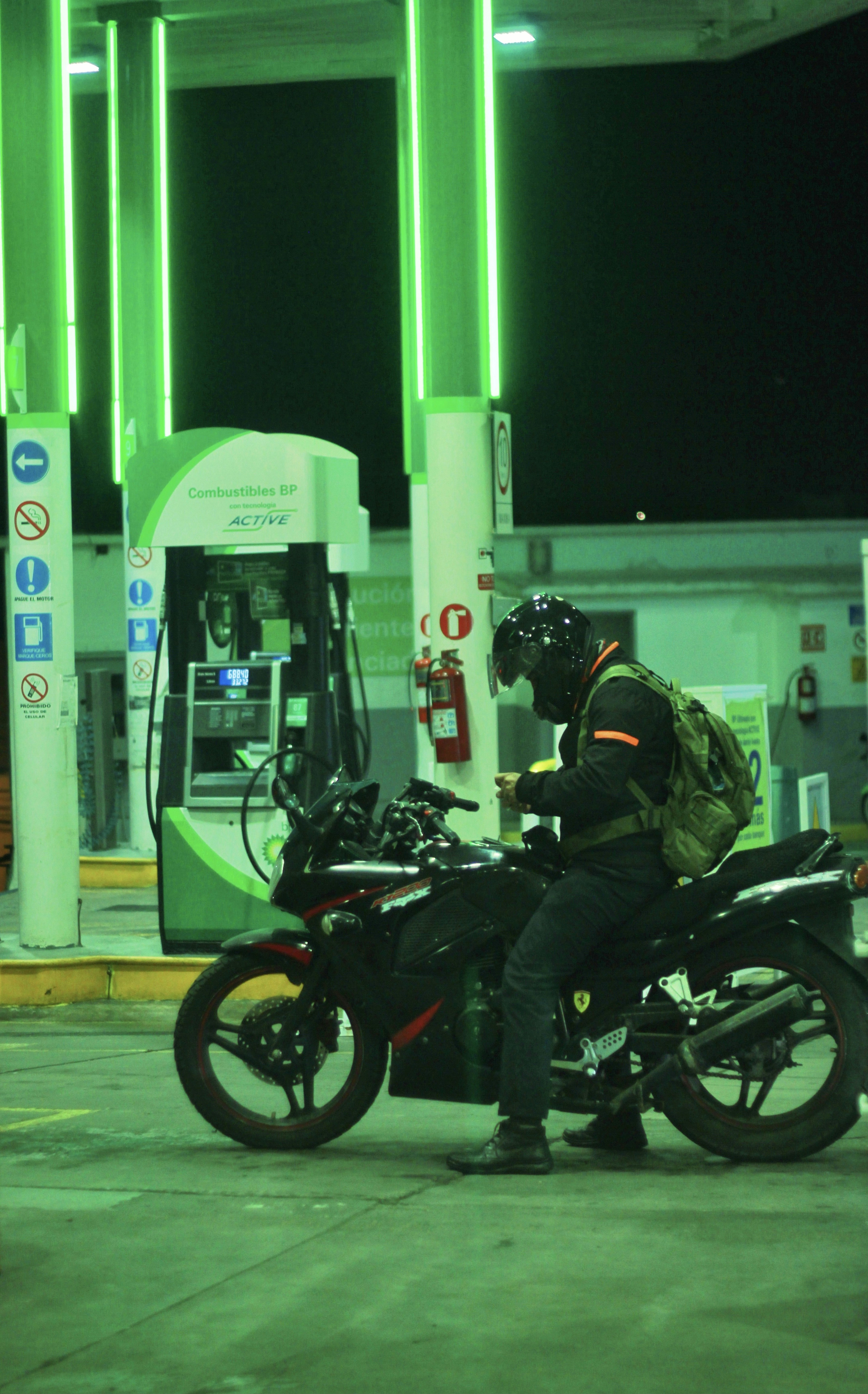 Seorang pria duduk di atas sepeda motor di pompa bensin