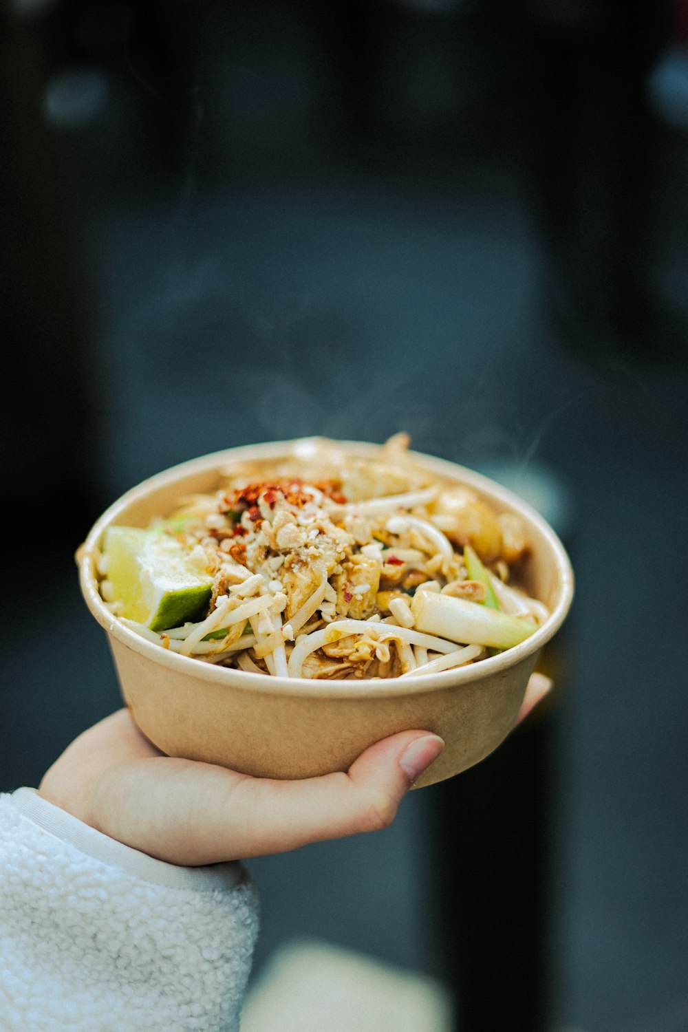 a person holding a bowl of food in their hand