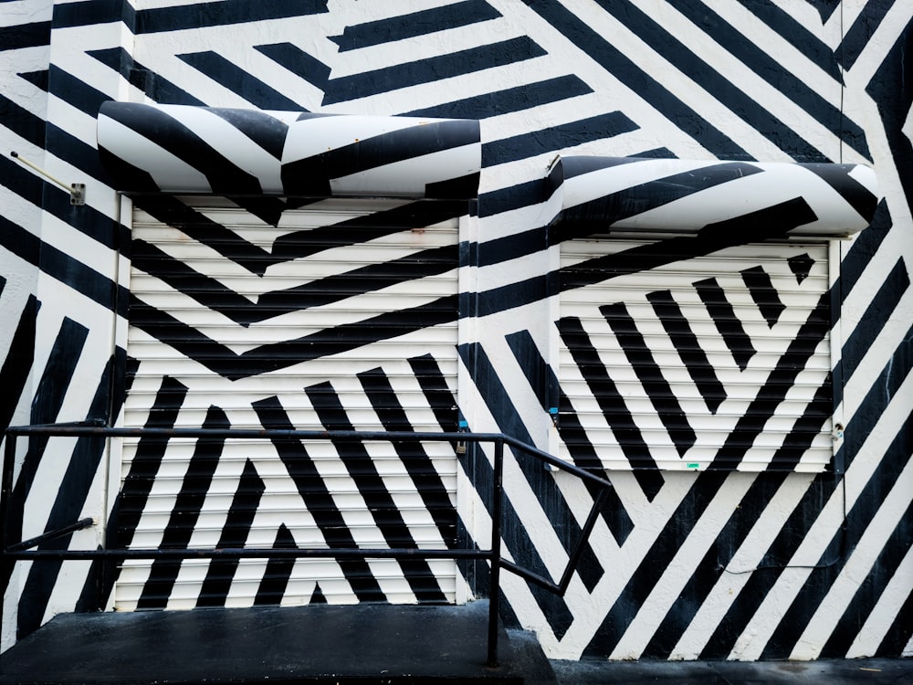 a black and white striped wall with a metal handrail