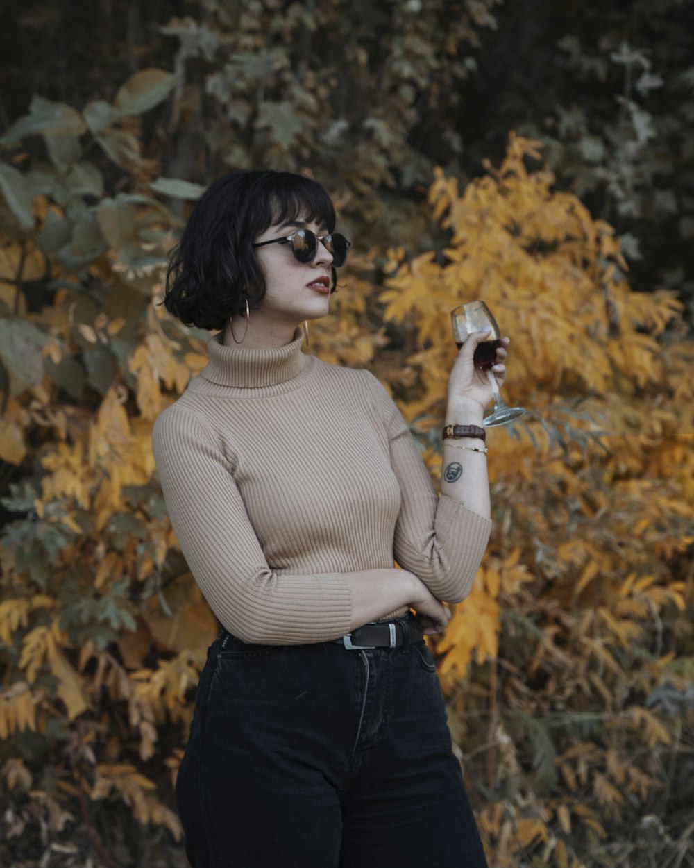 a woman in a turtle neck sweater holding a glass of wine