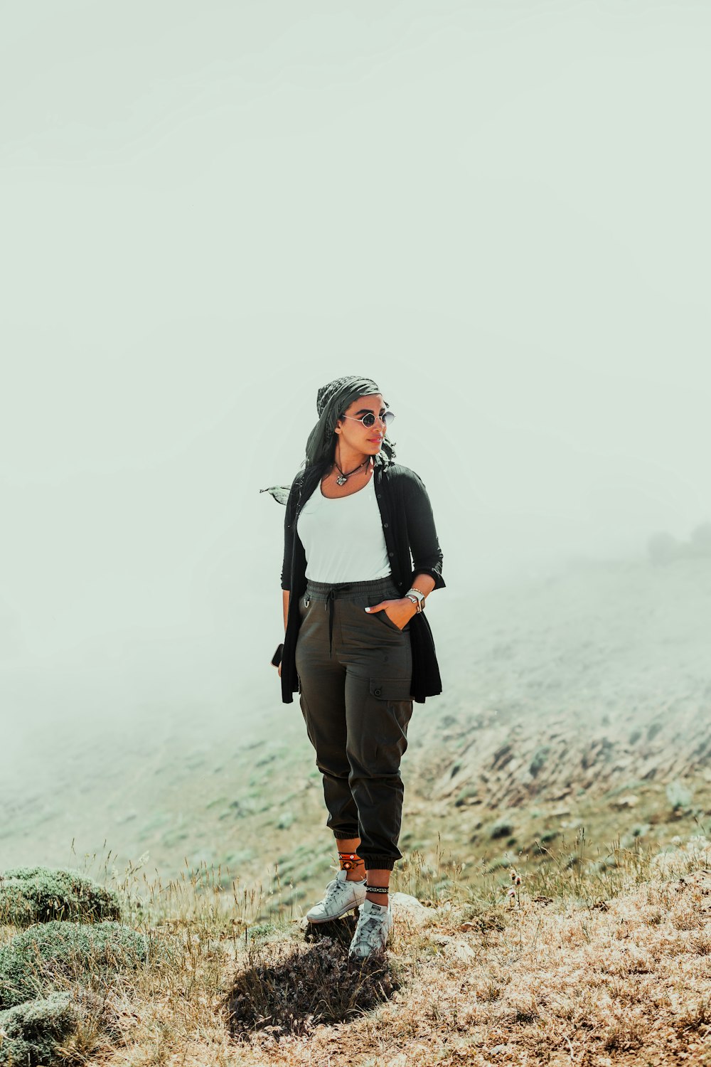 a woman standing on top of a grass covered hillside