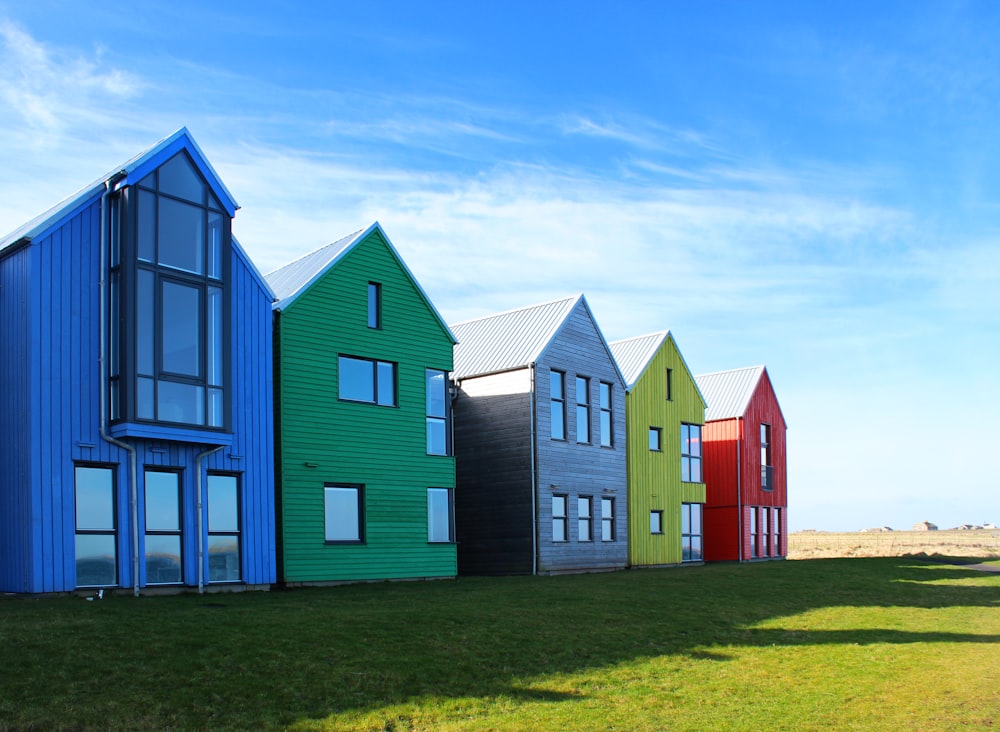 a row of colorful houses sitting on top of a lush green field