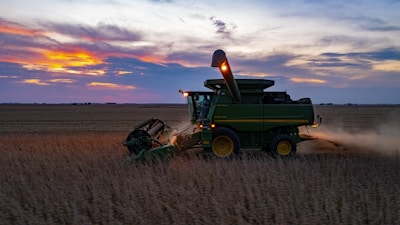 a combine harvesting a field at sunset