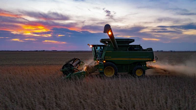 a combine harvesting a field at sunset