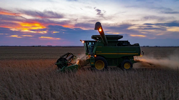 a combine harvesting a field at sunset