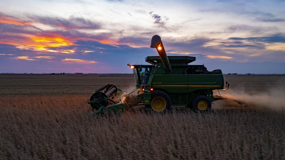 a combine harvesting a field at sunset