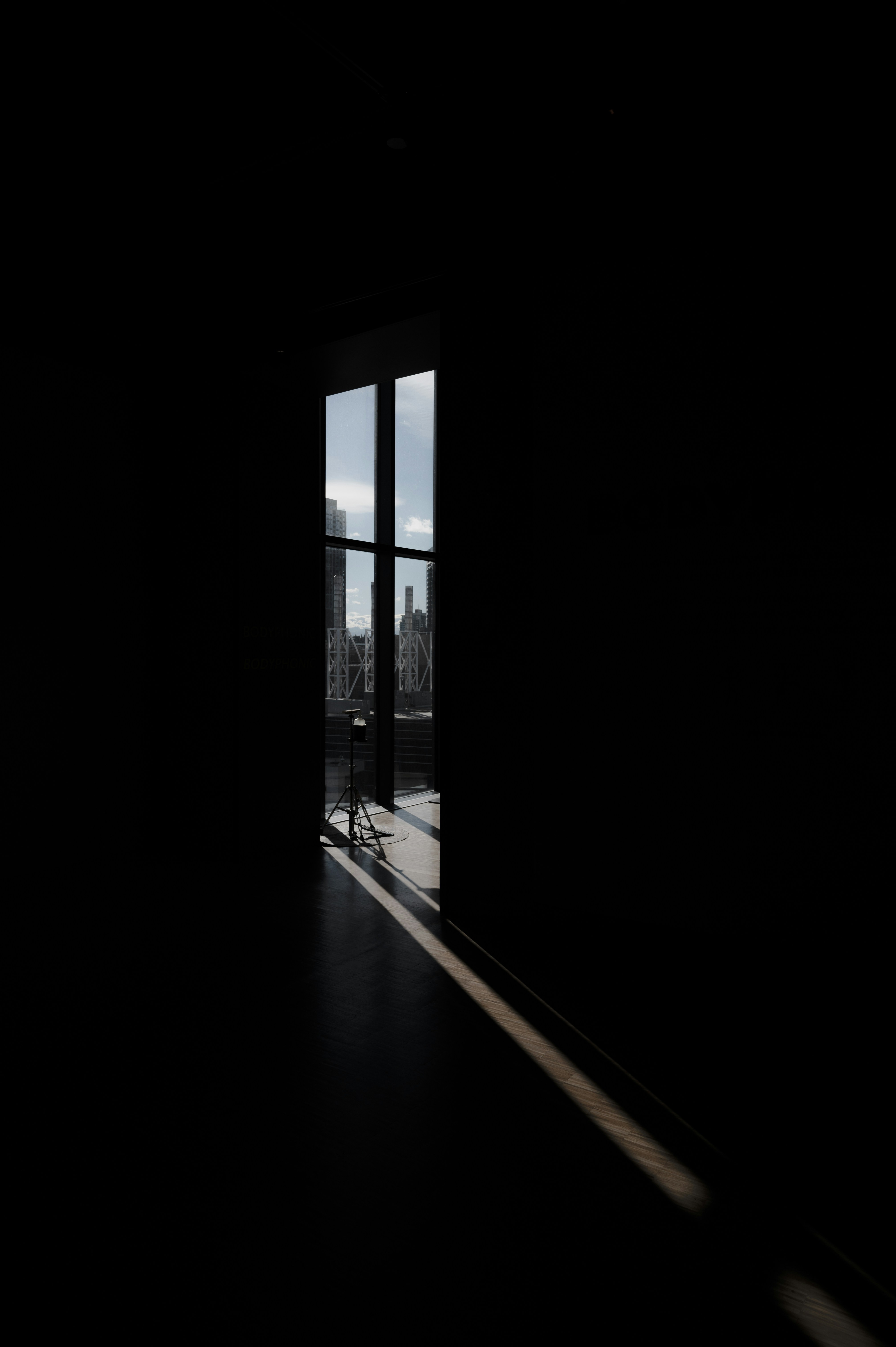 Una puerta abierta en una habitación oscura con vistas a una ciudad foto –  Imagen de Luz gratuita en Unsplash, image size:3000x4509