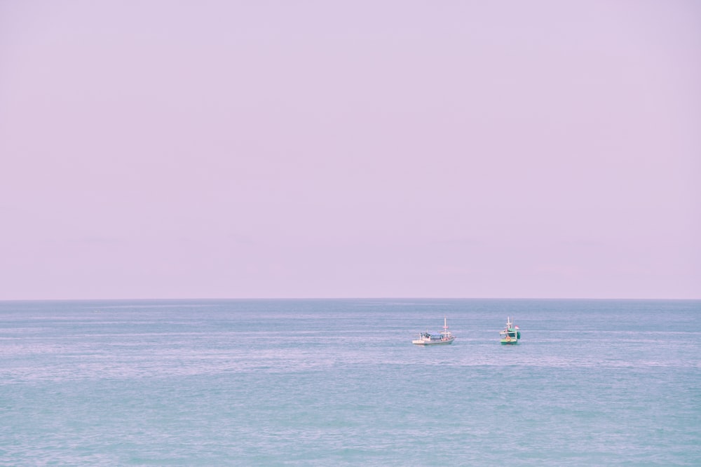 Un par de barcos flotando sobre una gran masa de agua