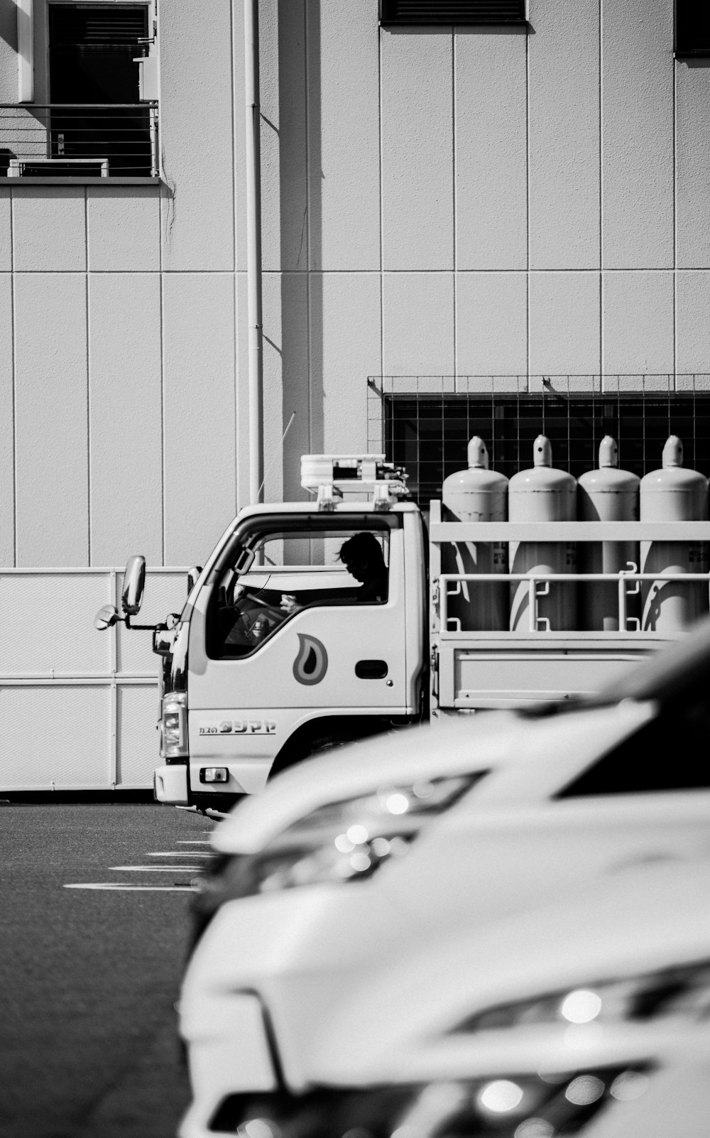 a black and white photo of a truck parked in front of a building