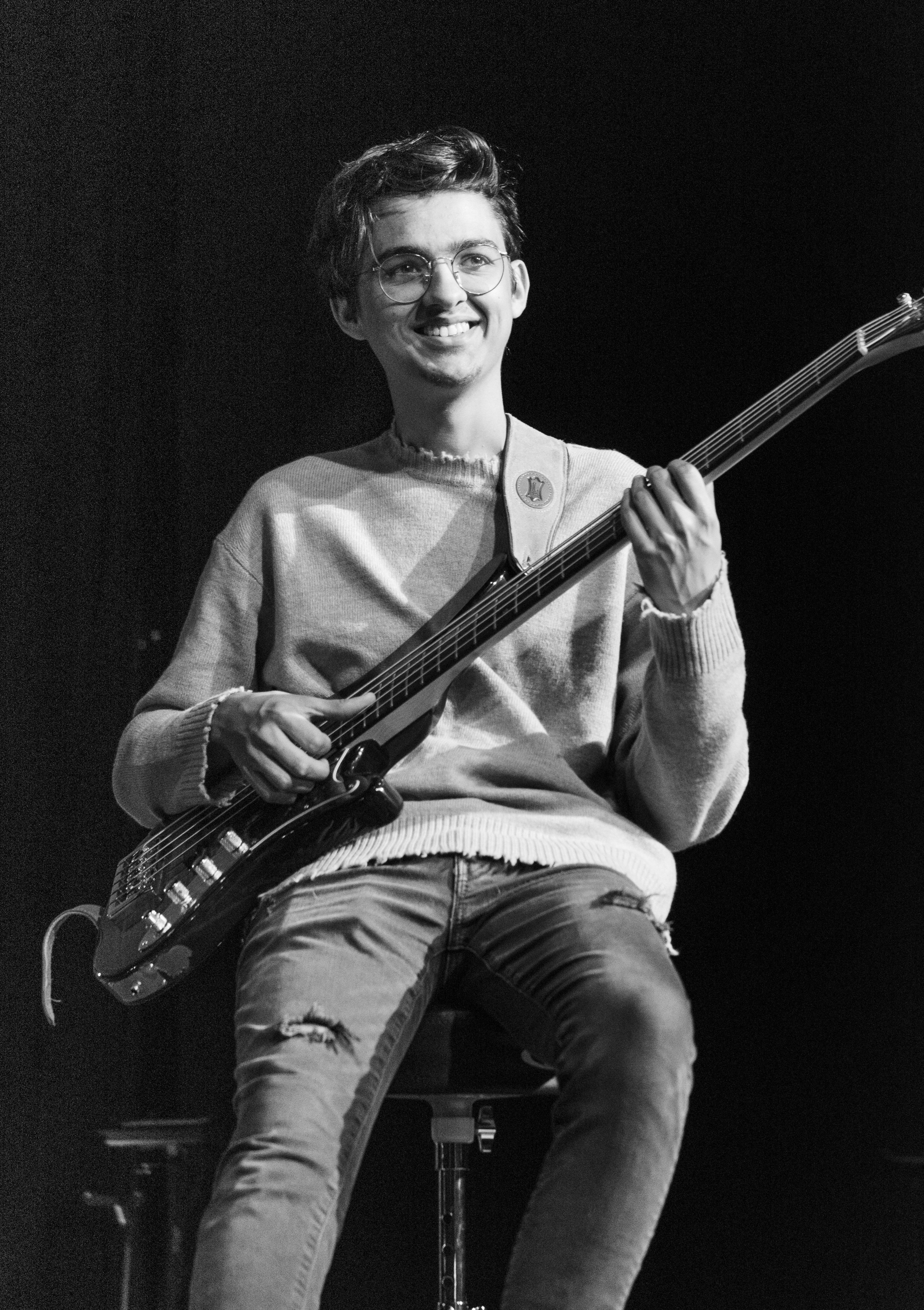 a man sitting on top of a stool holding a guitar