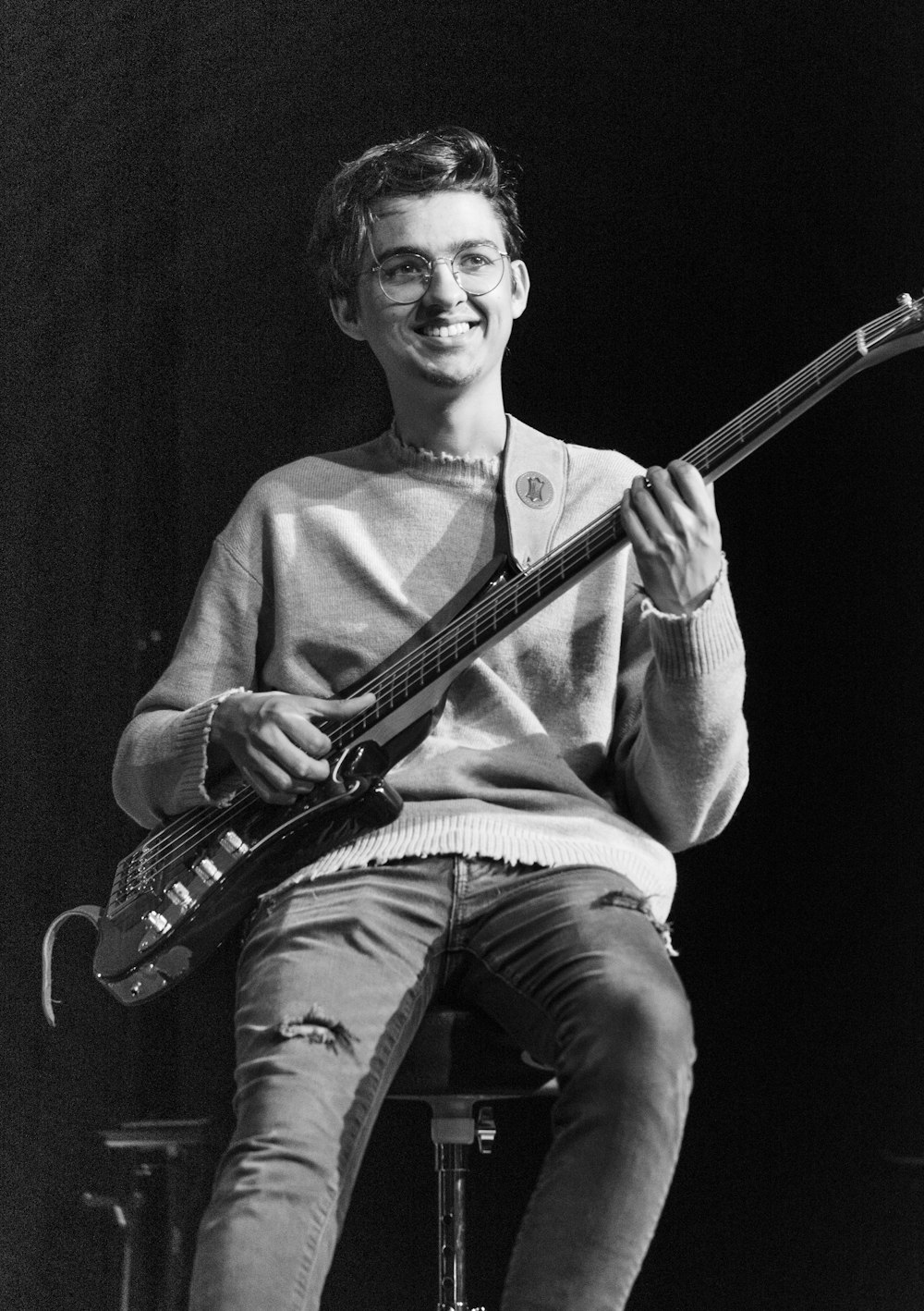 a man sitting on top of a stool holding a guitar