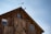 A close-up photo of a handcrafted metal weathervane mounted on a rustic barn roof against a clear blue sky.