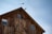 A close-up photo of a handcrafted metal weathervane mounted on a rustic barn roof against a clear blue sky.